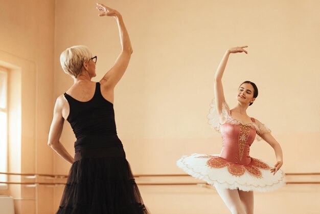 Ballerine souriante et son instructeur répétant dans un studio de ballet