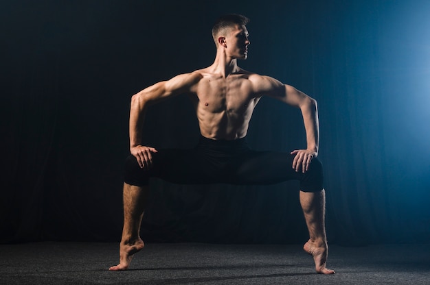 Ballerino en collants posant avec les jambes écartées