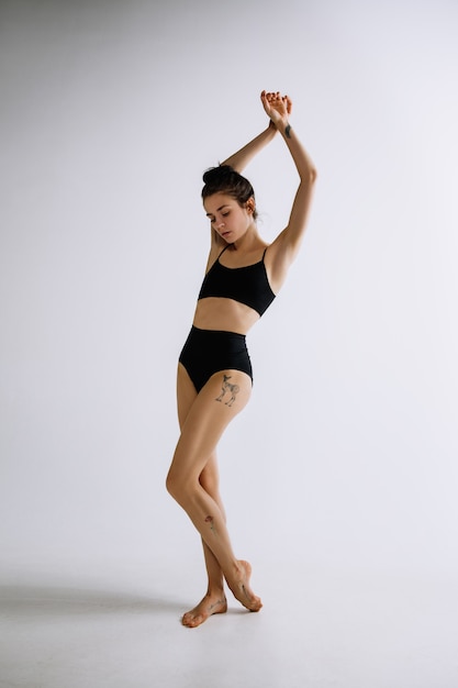 Photo gratuite ballet de mode. jeune danseuse de ballet en body noir sur fond blanc.