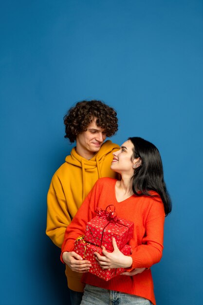 Ballon coeur, embrassant. Beau couple amoureux sur fond bleu studio. Saint Valentin, amour, relation et concept d'émotions humaines. Copyspace. Jeune homme et femme ont l'air heureux ensemble.