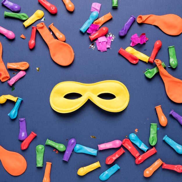 Ballons colorés avec des confettis colorés et un masque de carnaval jaune