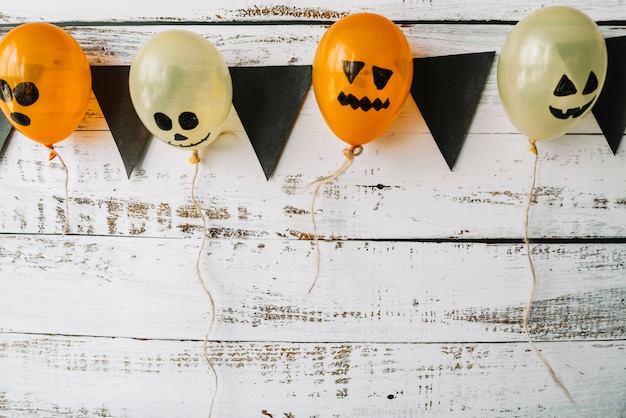 Photo gratuite ballons avec des visages représentés et des drapeaux noirs suspendus sur fond en bois