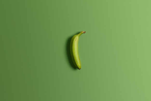 Banane entière verte non mûre sur fond de studio lumineux. Savoureux fruits tropicaux appétissants. Une alimentation saine, une collation nutritive et diététique saine. Vue de dessus et pose à plat. Tir horizontal. Concept alimentaire