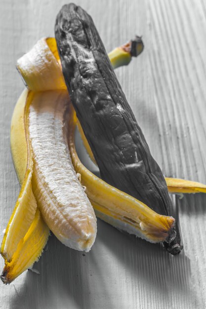 Banane fraîche et pourrie sur fond de bois