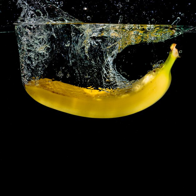 Banane jaune éclabousser dans l&#39;eau sur fond noir