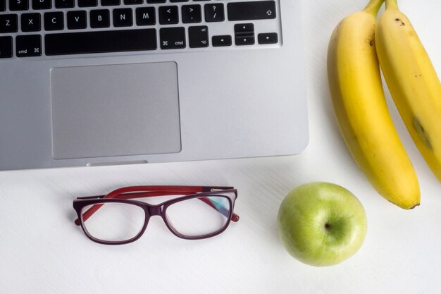 Bananes et pommes près d&#39;un ordinateur portable et de lunettes