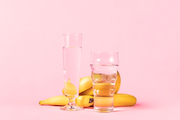 Photo gratuite bananes et variété de verres avec de l'eau