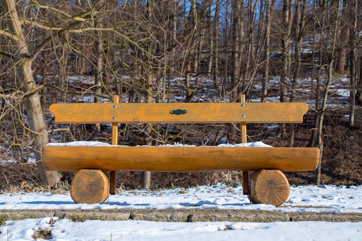 Photo gratuit banc en bois dans un parc couvert de neige par une journée d'hiver ensoleillée
