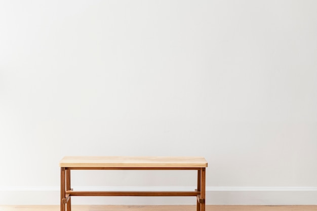 Banc en bois par un mur blanc