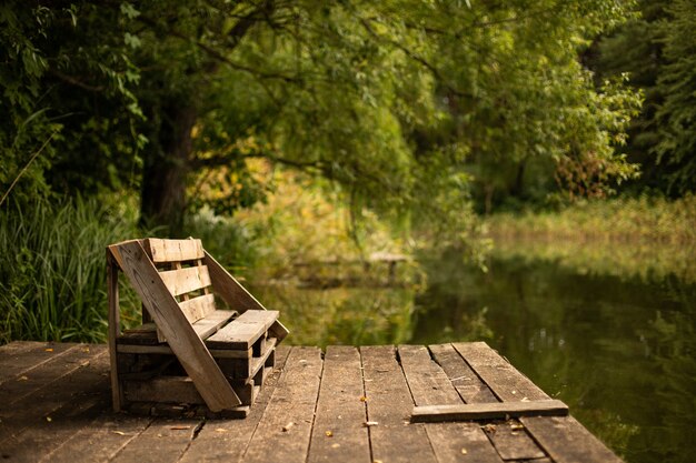 Banc en bois sur le pont sur le lac entouré de greens