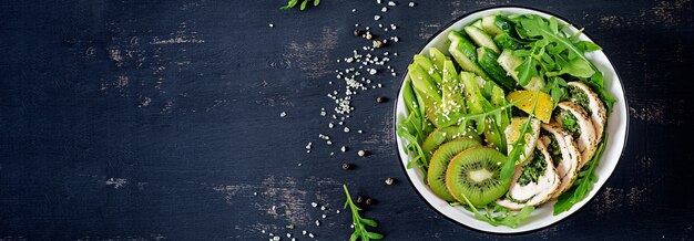 Bannière. Bol à Bouddha avec filet de poulet, avocat, concombre, salade de roquette fraîche et sésame.