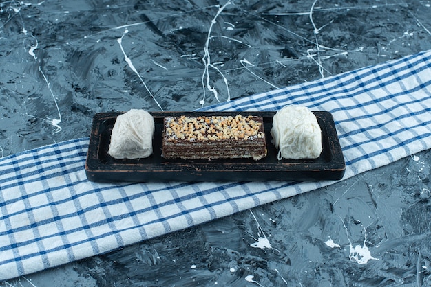 Photo gratuite barbe à papa et gaufre au chocolat sur une plaque en bois sur un torchon, sur le fond bleu.