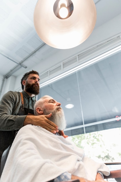 Photo gratuite barber prépare le client pour la coupe au salon de coiffure