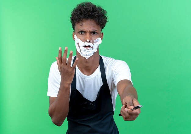 Barbier jeune homme strict portant l'uniforme avec de la crème à raser