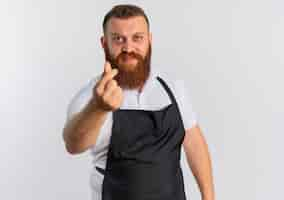 Photo gratuite barbier professionnel barbu en tablier se frottant les doigts faisant de l'argent geste debout sur mur blanc