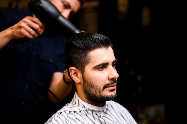 Barbier séchant les cheveux de son client