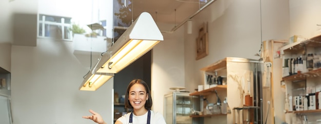 Photo gratuite une barista asiatique heureuse travaille dans un café. elle traite les commandes des clients derrière le comptoir.