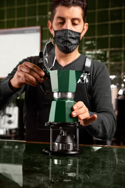 Barista coup moyen avec masque préparant le café