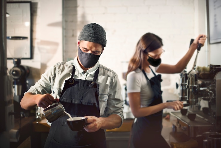 Photo gratuit barista dans la marque de visage au café dans la nouvelle normalité