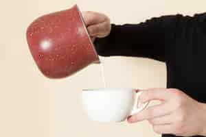 Photo gratuite barista faisant du café avec du lait versant sur un bureau blanc