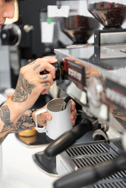 Barista masculin avec des tatouages à l'aide de la machine à café du café