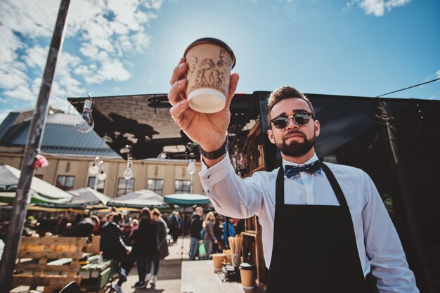 Photo gratuite un barista à la mode soigné dans des verres prend une pause-café et savoure un café. il y a une belle journée d'été ensoleillée.