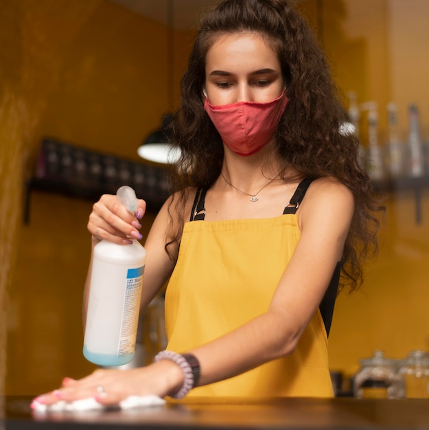 Barista portant un masque médical lors du nettoyage dans le café