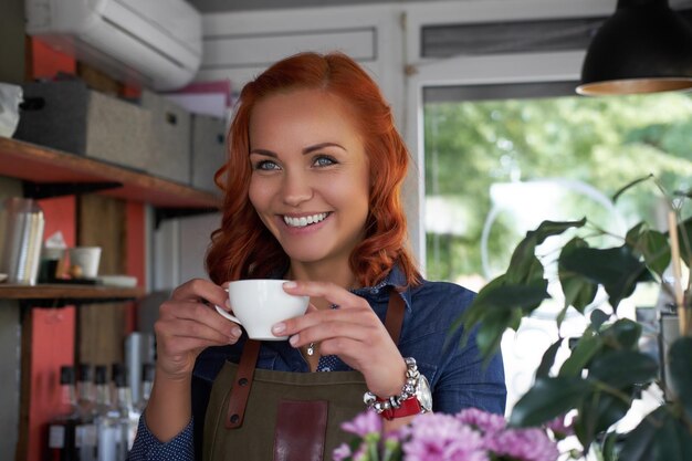 Une barista rousse beauté boit un café, au café.