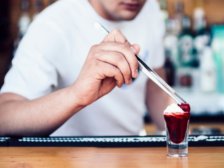 Photo gratuit barman anonyme décorant un shot rouge avec de la crème et des fruits