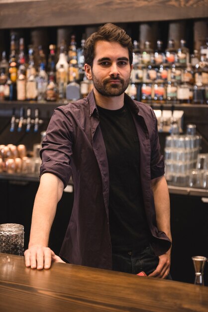 Barman confiant debout au comptoir du bar