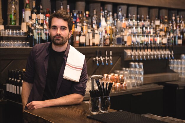 Barman confiant debout au comptoir du bar