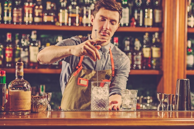 Un barman expert prépare un cocktail en boîte de nuit ou au bar.