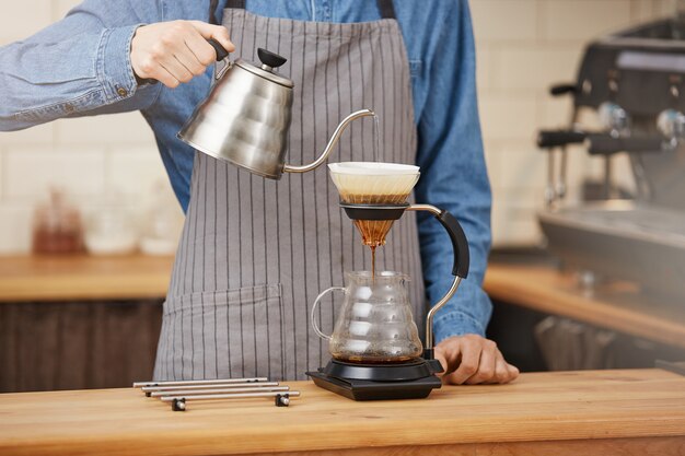 Barman faisant du café alternatif à l'aide d'un infuseur manuel, en versant de l'eau.