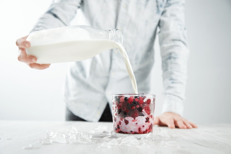Photo gratuit barman homme verse du lait de bouteille vintage au verre avec un cocktail laiteux avec des baies congelées