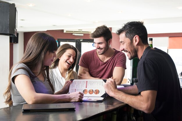 Barman montrant le menu aux clients au comptoir du bar