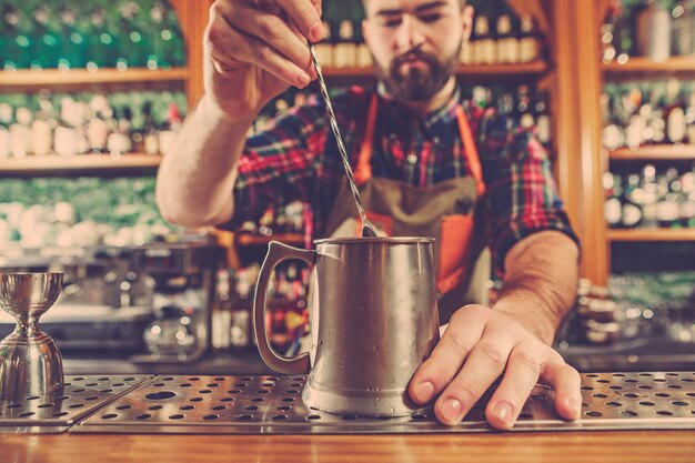 Le barman prépare un cocktail alcoolisé au comptoir du bar sur l'espace bar