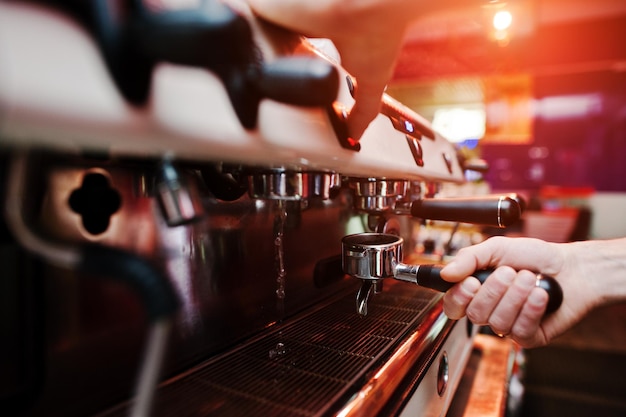 Barman professionnel à la machine à café avec de la vapeur faisant de l'espresso dans un café