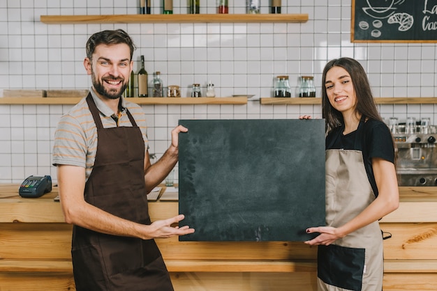 Barmen joyeux présentant tableau noir