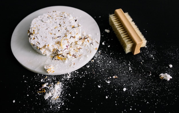 Photo gratuite barre de savon cassée sur un tableau blanc près de la brosse sur une surface noire