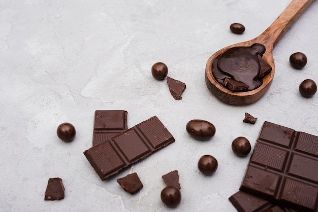 Barres de chocolat à angle élevé et cuillère en bois avec sirop de chocolat