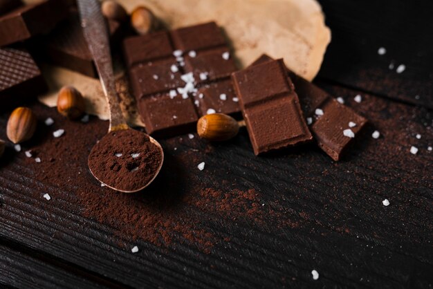 Barres de chocolat à angle élevé et cuillère avec de la poudre de cacao