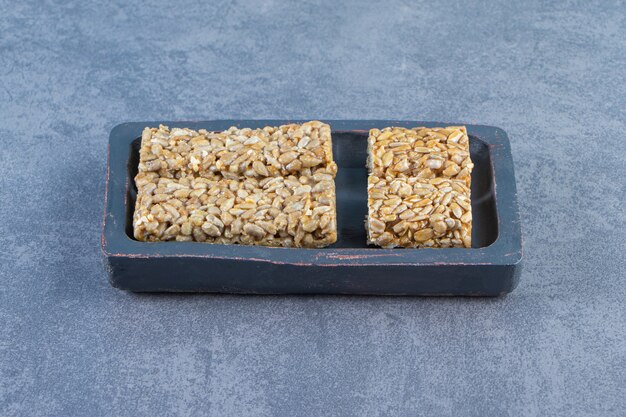 Barres granola dans une assiette en bois , sur fond de marbre.