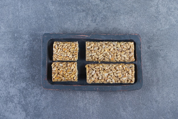 Barres granola dans une assiette en bois , sur fond de marbre.