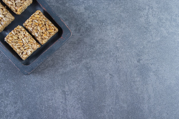 Barres granola dans une assiette en bois sur la surface en marbre