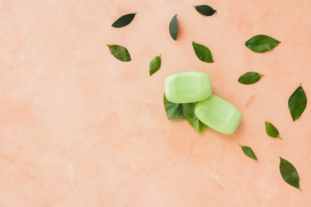 Barres de savon et feuilles sur fond orange avec espace de copie