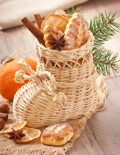 Bas de Noël en osier rempli de biscuits, bâtons de cannelle, citron confit et anis étoilé