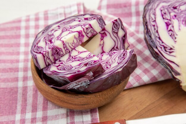 Bas vue rapprochée chou rouge dans des bols torchon à carreaux blanc violet sur une planche à découper sur une table grise