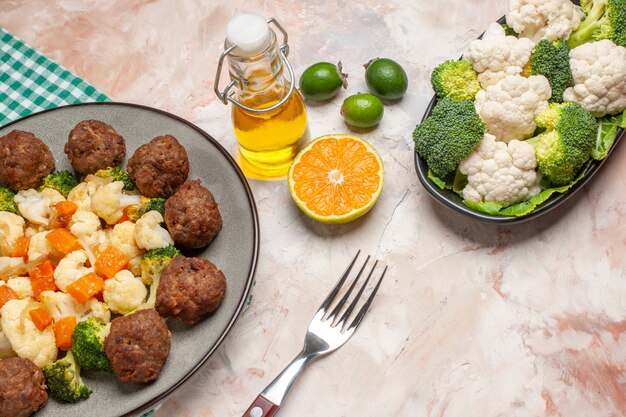 Bas vue rapprochée salade de brocoli et chou-fleur et boulette de viande sur assiette serviette à carreaux vert et blanc une fourchette huile crudités sur assiette feykhoas tranche de citron sur fond isolé nu