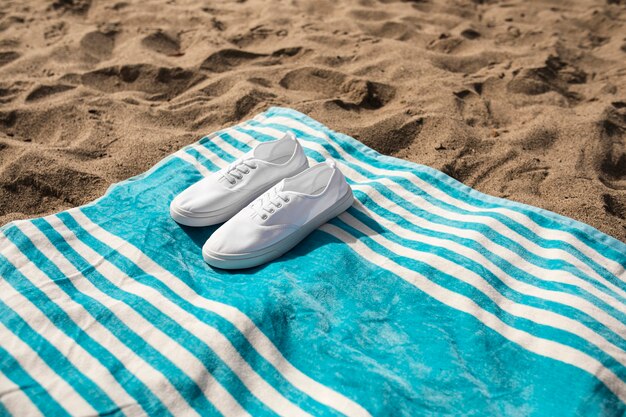 Baskets blanches sur la photographie d'ambiance d'été de serviette de plage