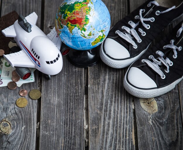 Baskets, globe terrestre et avion avec de l'argent